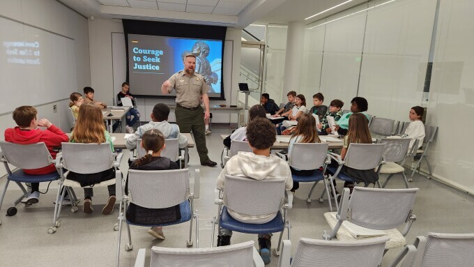 Ray Brundge speaks to a group of students in the Gateway Arch Visitor Center.