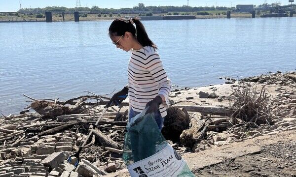Woman picks up trash along riverfront
